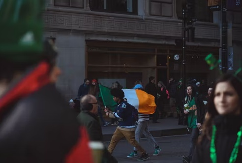 A boy waving Ireland flag in the street