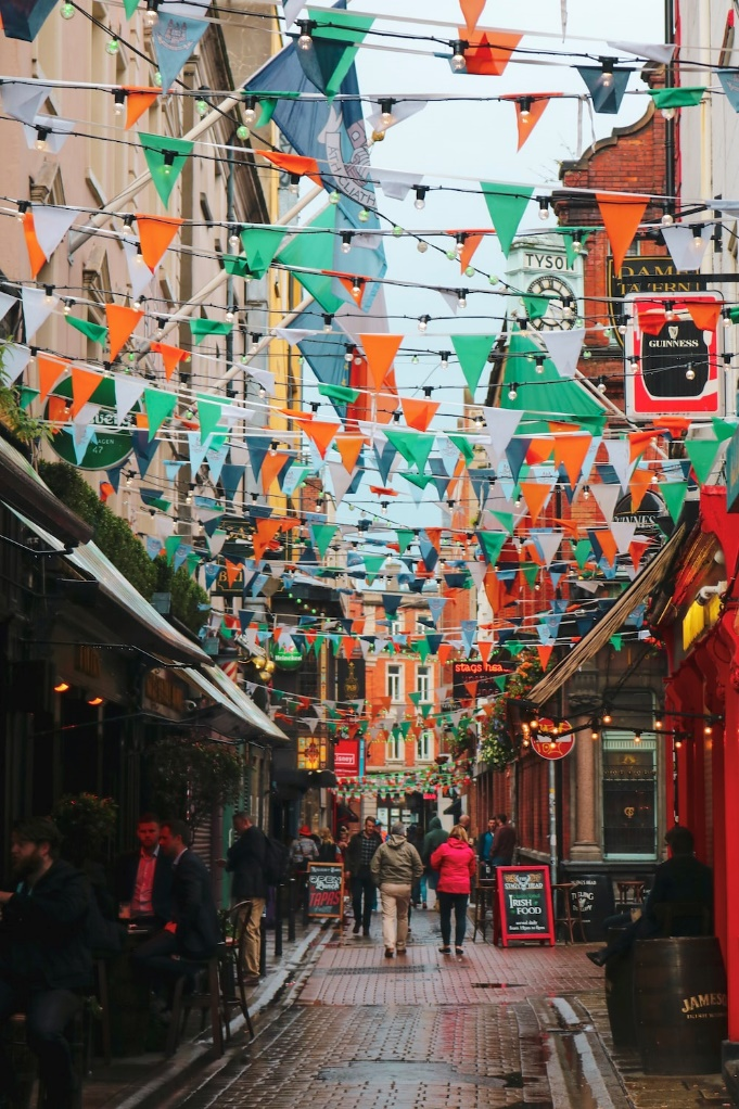 People walking in an Irish alley decorated with Irish flags