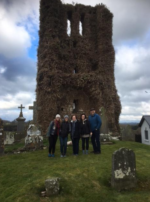 A family visiting their ancestral graveyard during a family history tour.